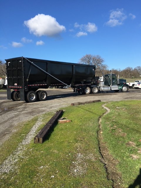 Tractor with a black high side demo end-dump trailer