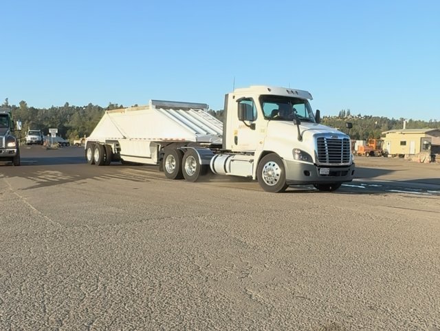 White tractor with a semi bottom-dump trailer